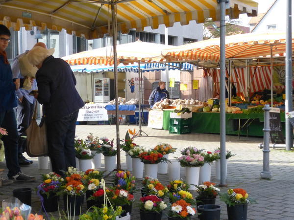 Wochenmarkt in Jügesheim mit Ständen für Blumen, Gemüse und Backwaren unter gestreiften Markisen